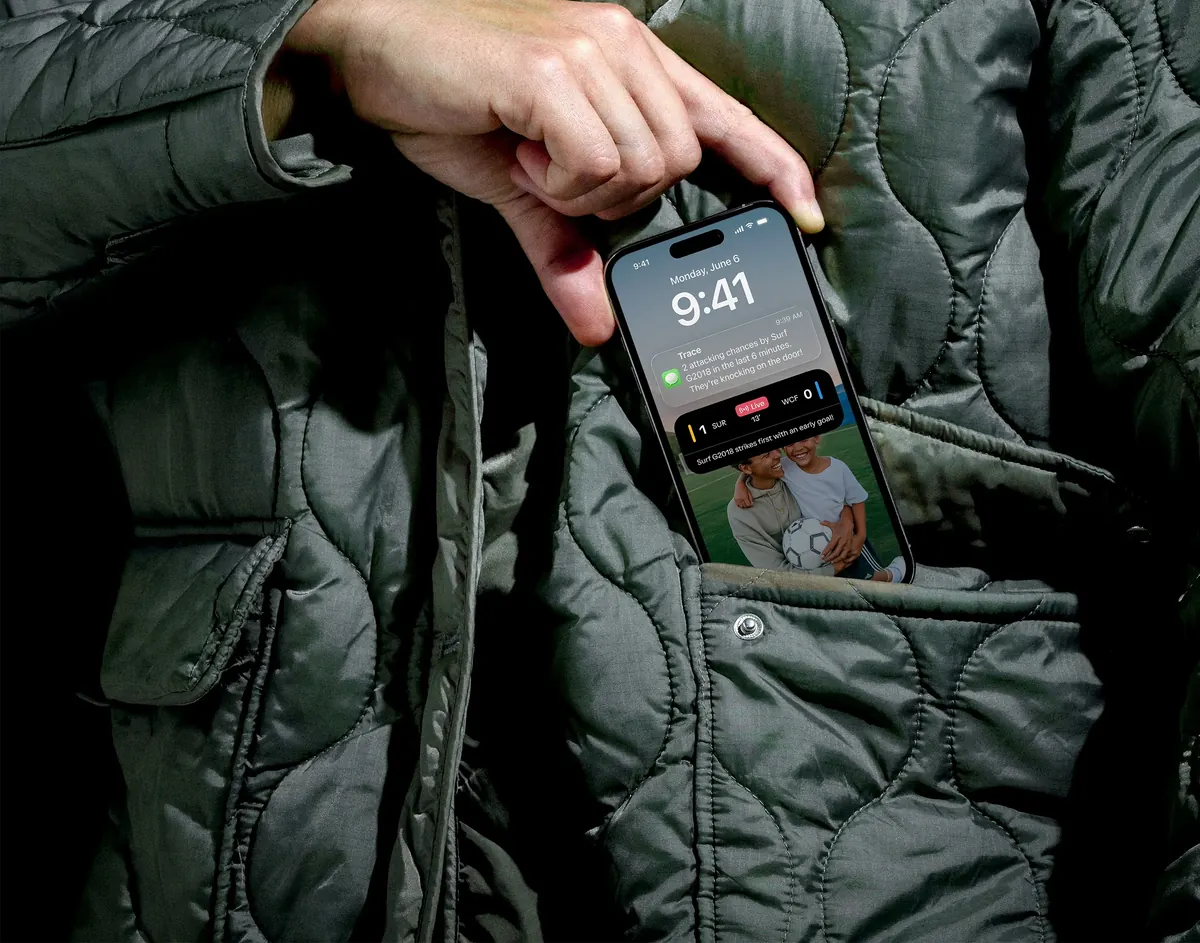 A parent pulls a phone with a Trace goal alert out of a jacket pocket