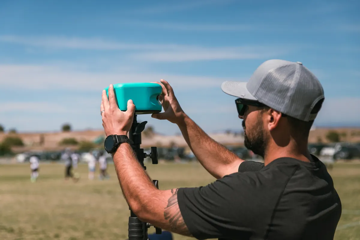 A coach sets the Trace camera on its tripod at midfield