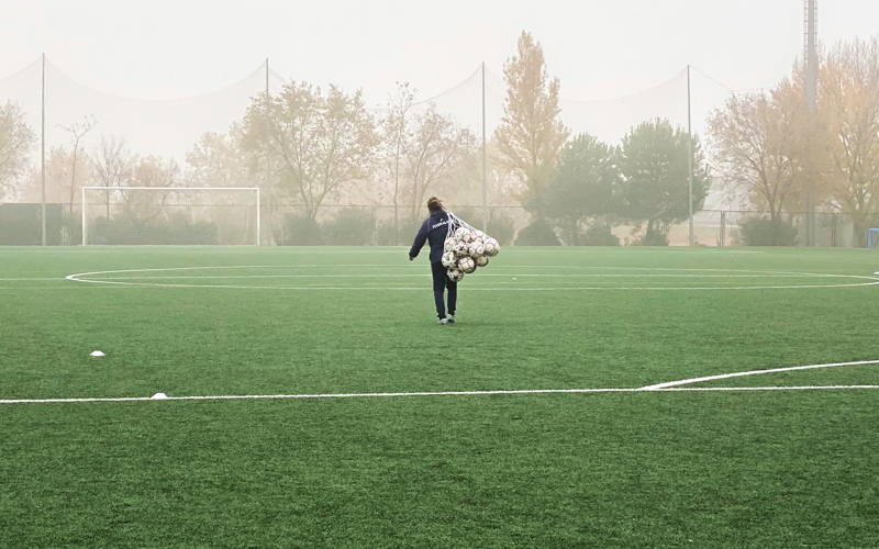 Carrying Balls On Foggy Field Person carries a net bag full of soccer balls across a foggy empty field