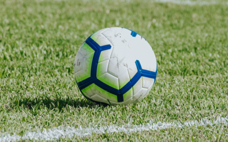 Close-up of a white and blue Nike soccer ball resting on the grass beside a field line