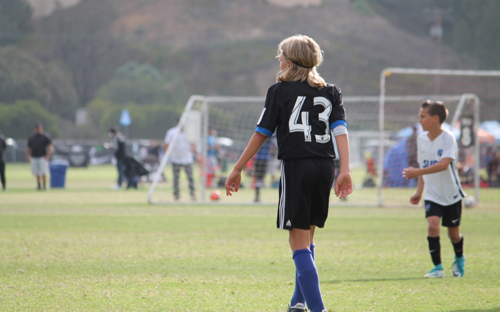 Youth soccer player in a black number 43 jersey stands on the field during a tournament