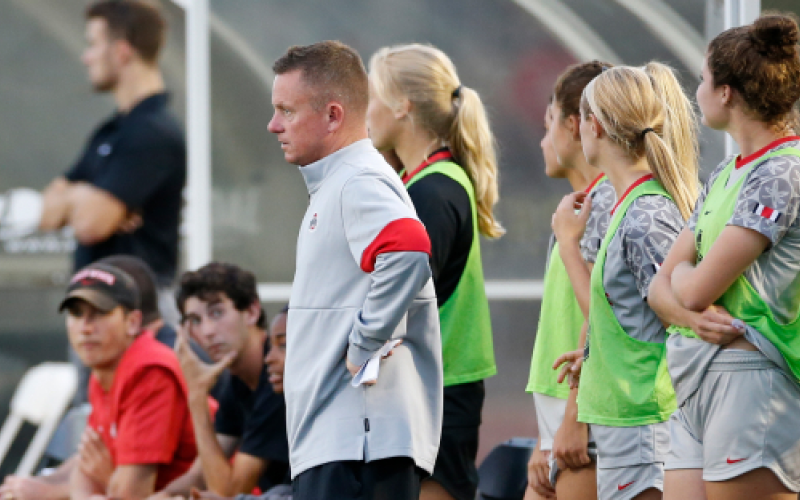 Ohio State Coach On Sideline Ohio State coach in grey and red jacket watching from the sideline beside players in green bibs
