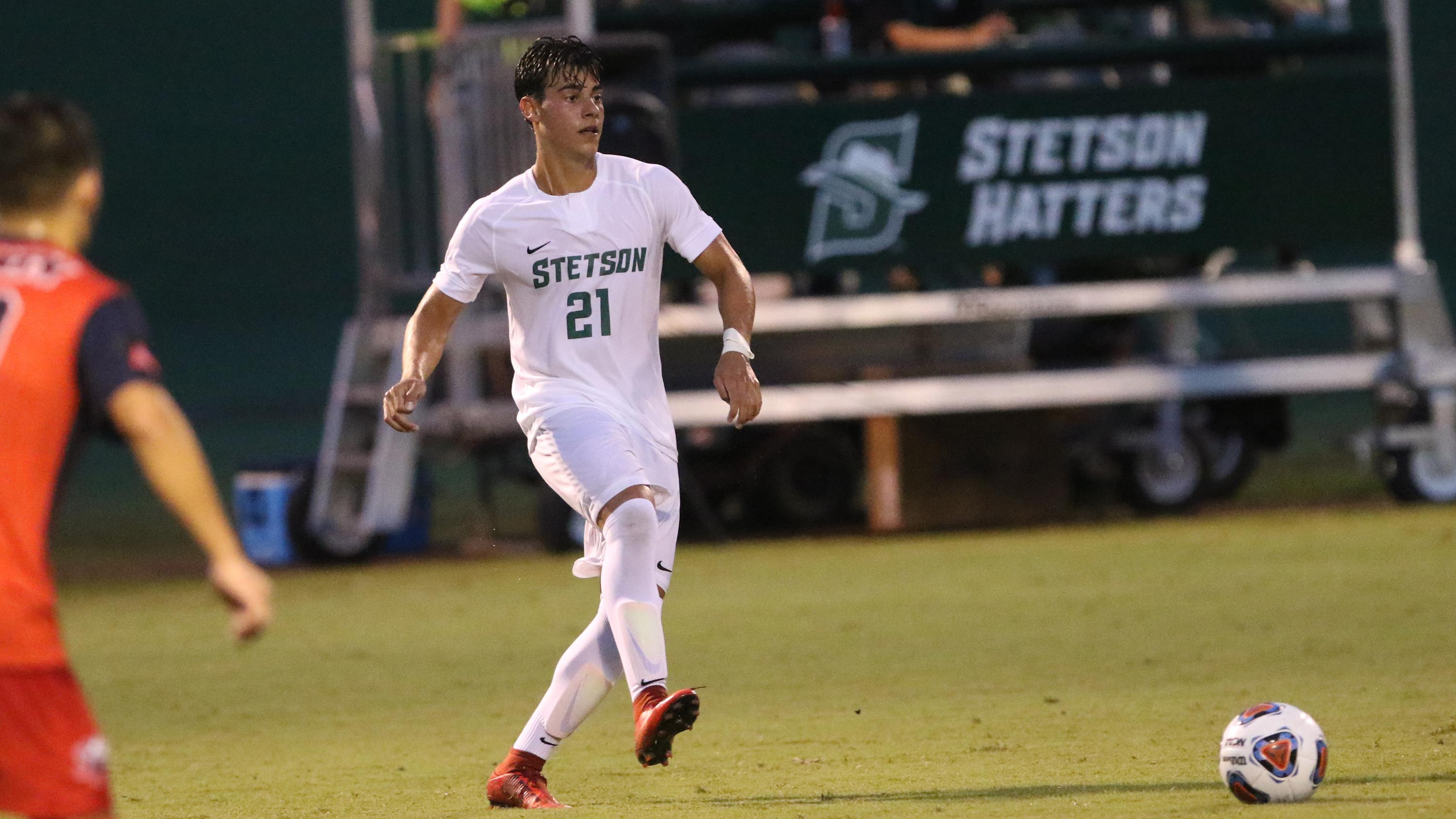 Stetson player number 21 in white kit passing the ball with Stetson Hatters banner behind