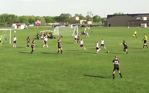 Wide view of a girls soccer match with player number 23 in black positioned in the foreground