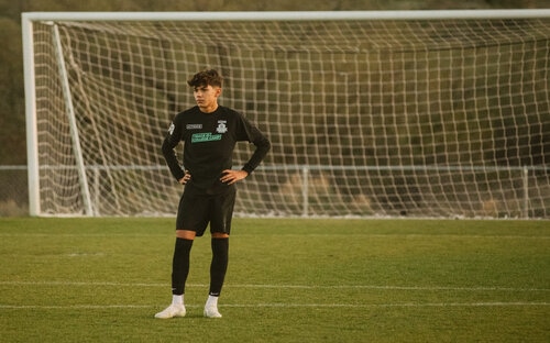 Player Standing By Goal Teenage soccer player in black standing with hands on hips in front of an empty goal