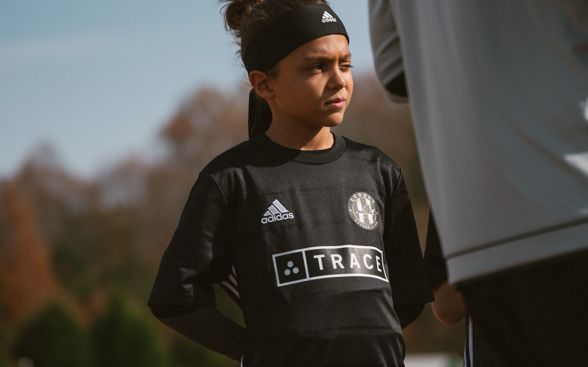 Young Player On Sideline Young player in a black Trace kit and headband looking off to the side on the field