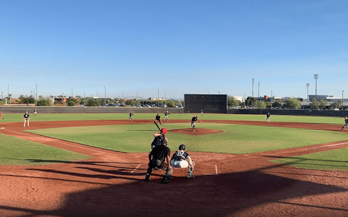 Youth baseball game viewed from behind home plate, with batter, catcher and umpire on the diamond.