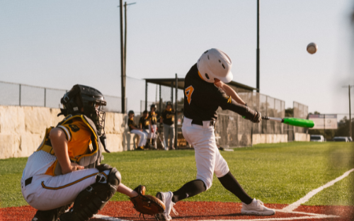 Baseball Batter Hitting Ball Youth baseball batter swinging and connecting with the ball as the catcher crouches behind
