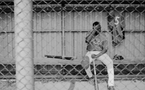 Dejected Player In Dugout Black-and-white photo of a baseball player sitting alone in the dugout with a hand over his face