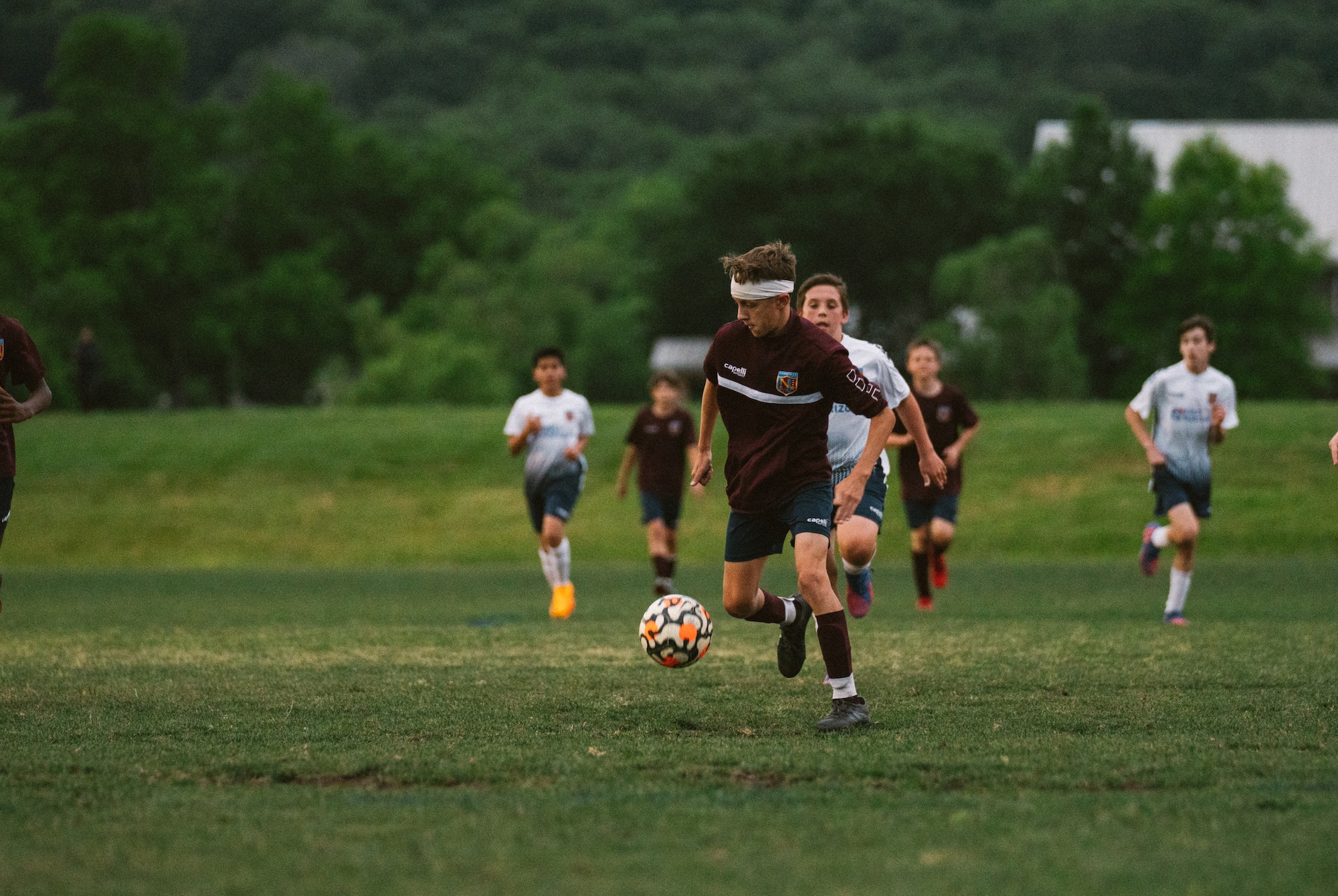 Soccer Player Dribbling Upfield Youth boys soccer player in a maroon jersey dribbling the ball upfield as opponents chase