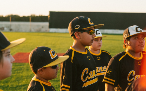 Baseball Team At Sunset Youth baseball players in black-and-gold uniforms and caps lined up on the field at sunset