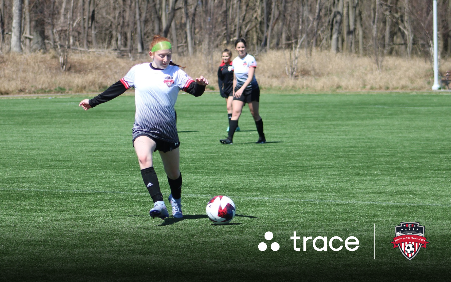 South Shore Player Dribbling Girl in a white and red South Shore kit dribbling a ball, with Trace logos