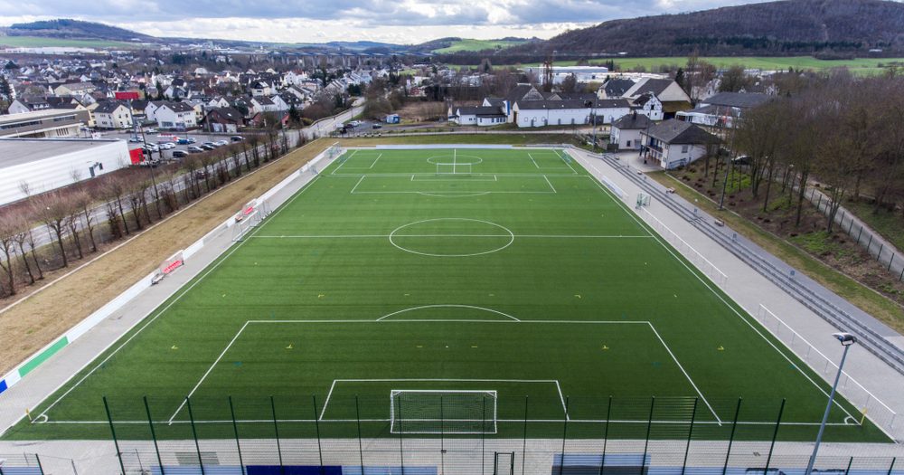 Aerial View Soccer Field Aerial view of an empty green turf soccer field with a town and hills behind