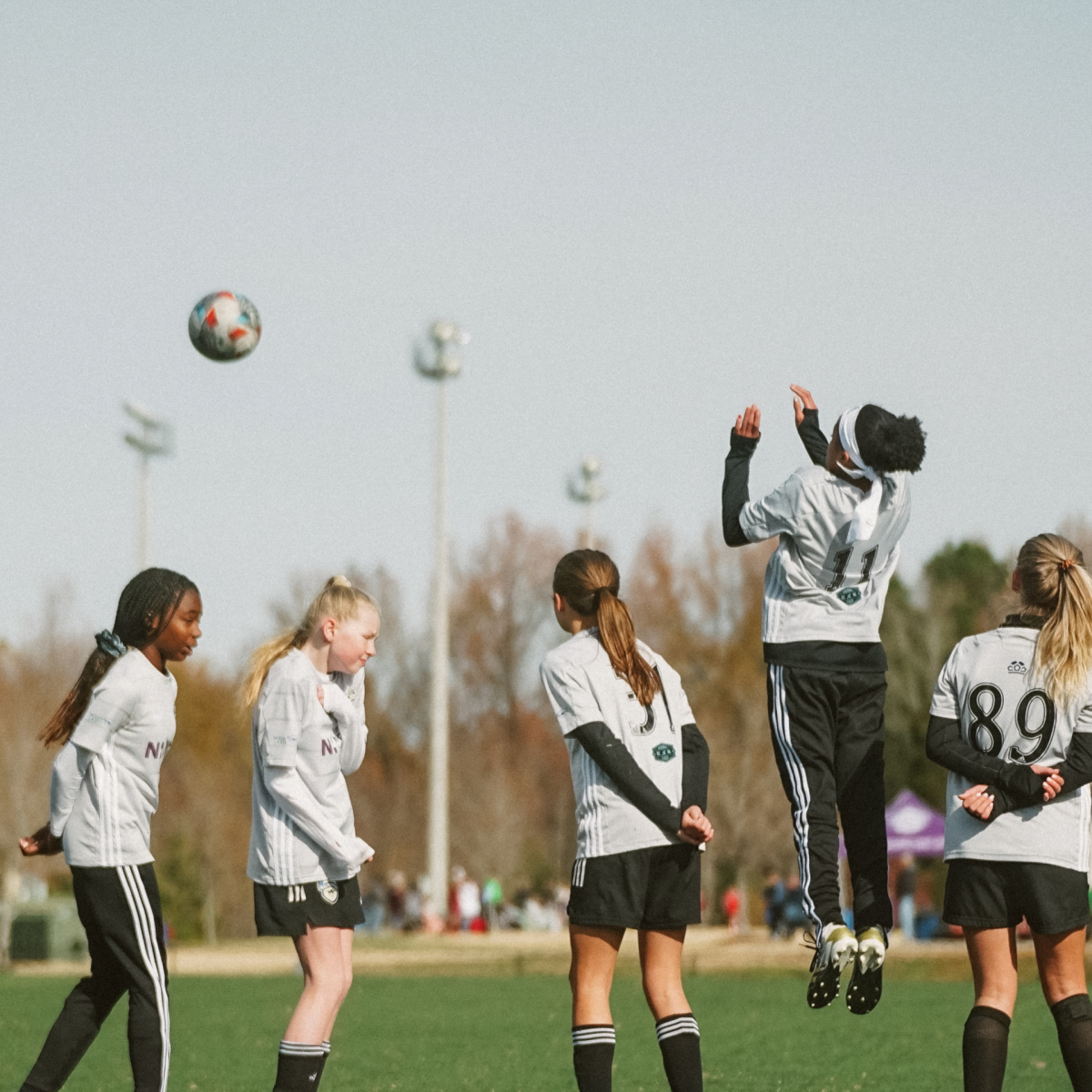 Defensive Wall Free Kick Girls soccer defensive wall jumping to block a free kick as the ball flies overhead.