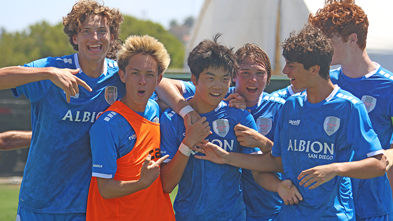 Albion San Diego Team Celebration Young male soccer players in blue Albion San Diego jerseys smiling and celebrating together.