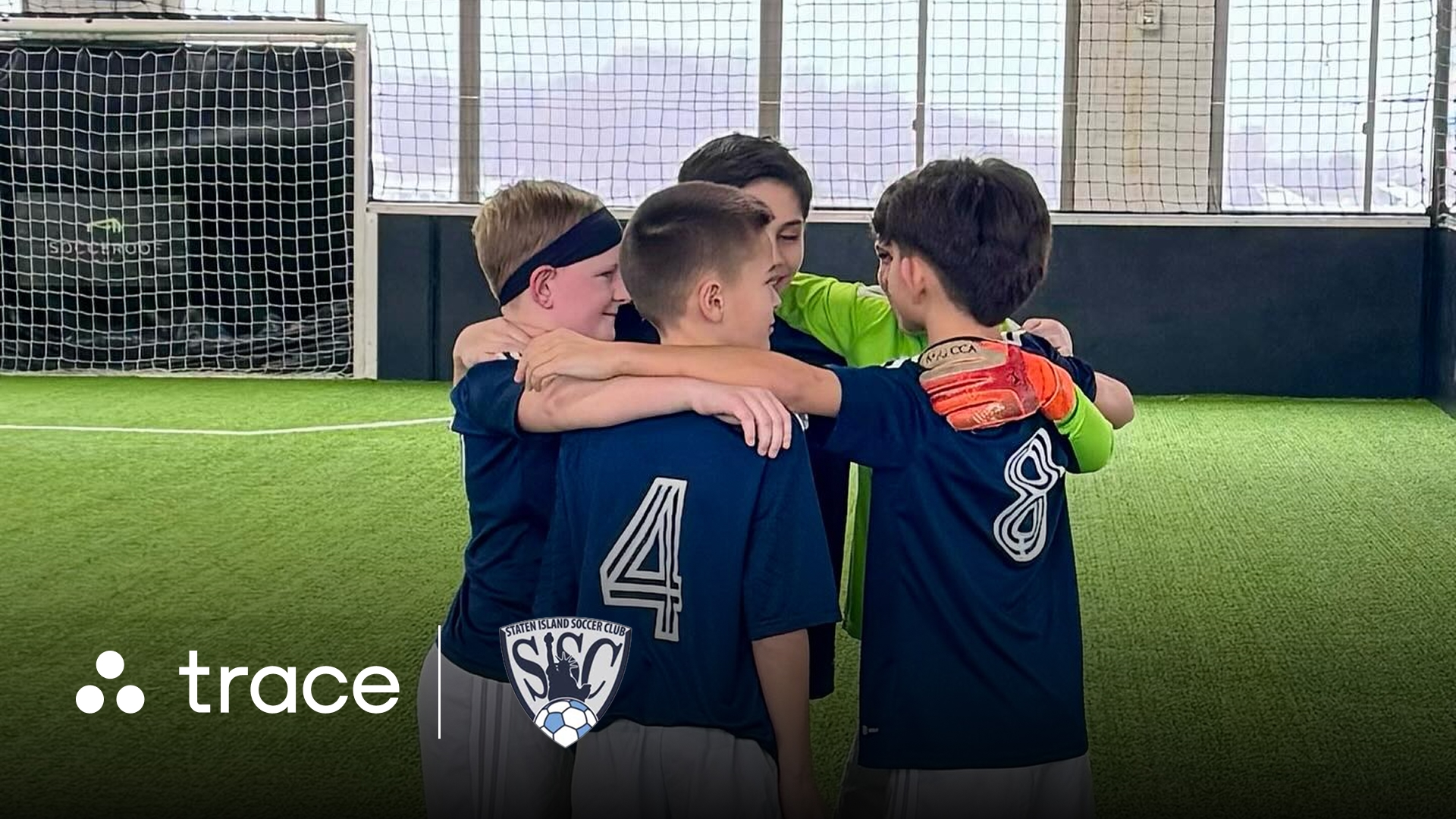 Staten Island SC Team Huddle Youth boys soccer team huddled arm-in-arm indoors, with Trace and Staten Island SC logos.