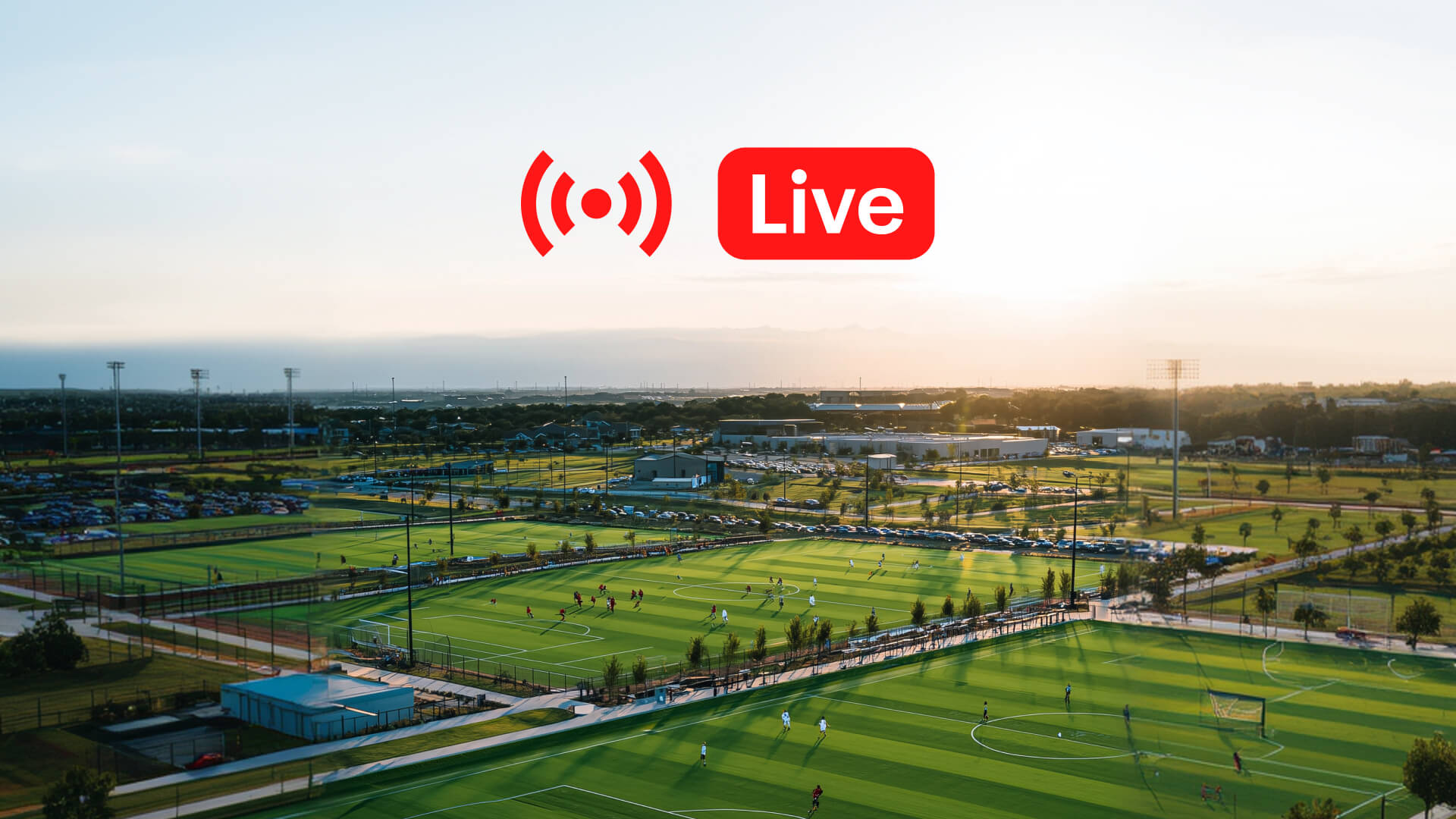Aerial view of a large multi-field soccer complex at sunset with a red Live streaming label.